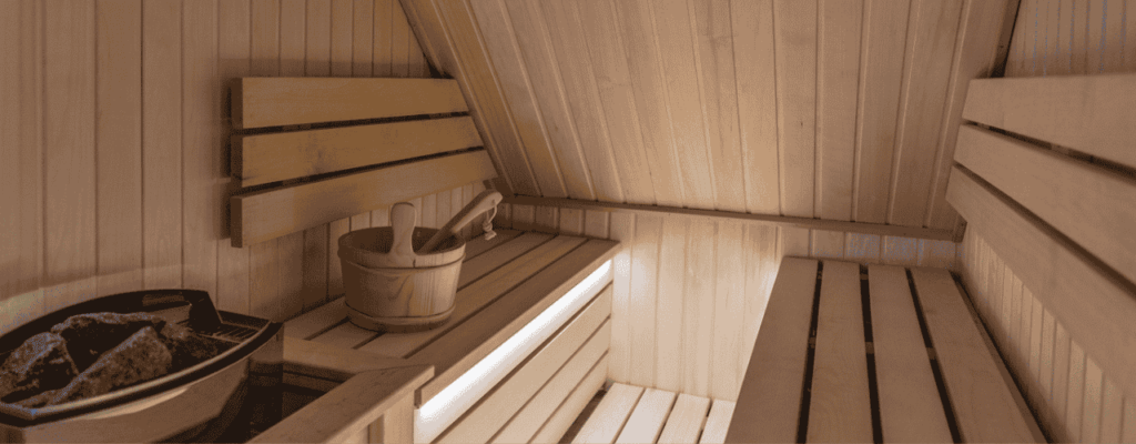 Electric sauna room with warm wooden walls and a sink for added comfort.