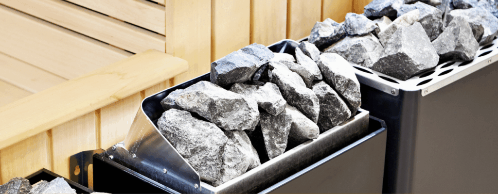 A metal bin filled with a pile of rocks, used for heating in an electric sauna.