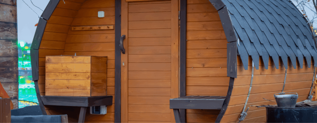 A wooden sauna with a bench and door, providing a serene environment for relaxation and wellness.