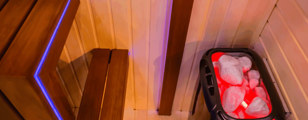 In the corner of an electric sauna, a red light glows softly, enhancing the room's ambiance.