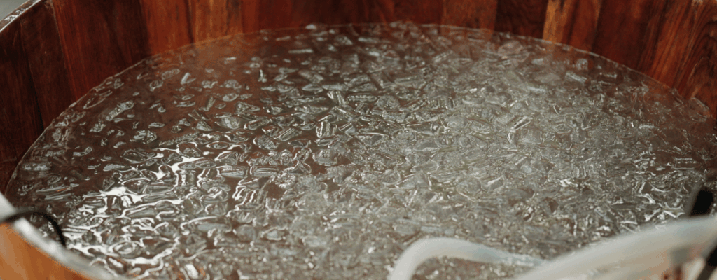 Filling the wooden tub with water and ice, preparing for ice bath therapy.
