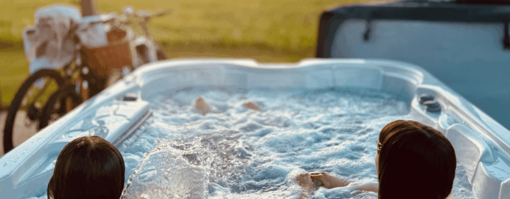 Two women unwind in a hot tub, watching a beautiful sunset together in a tranquil atmosphere.