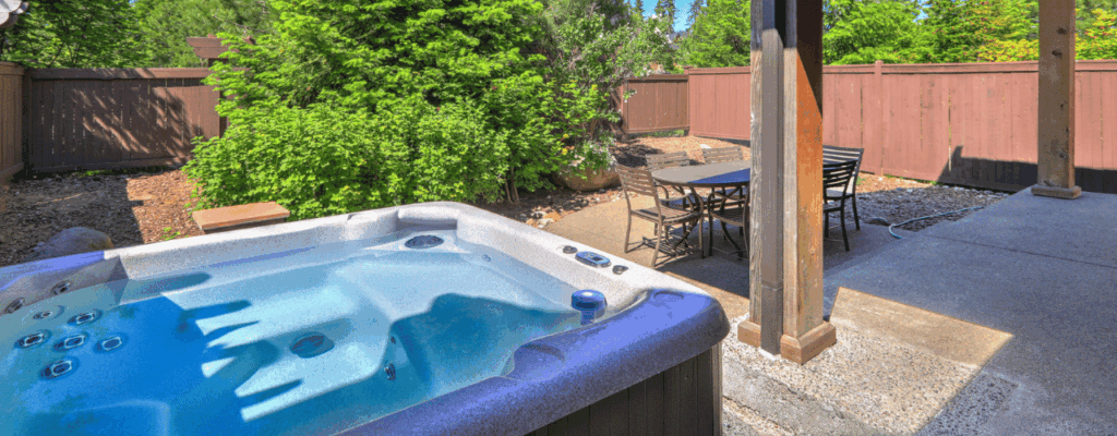 A hot tub sits in a backyard, surrounded by a patio and a table, creating a relaxing outdoor space.