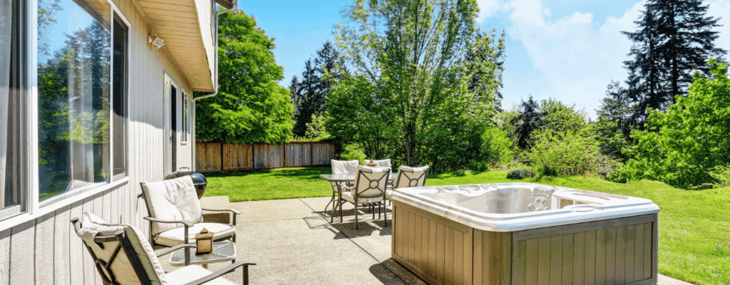 A hot tub on a patio surrounded by chairs and trees, creating a serene garden atmosphere.