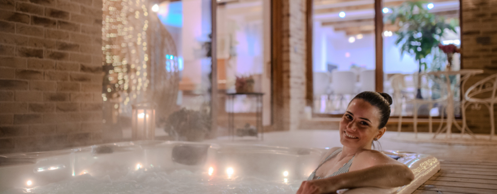 A woman enjoys a peaceful moment while relaxing in a hot tub, surrounded by serene water and a tranquil atmosphere.