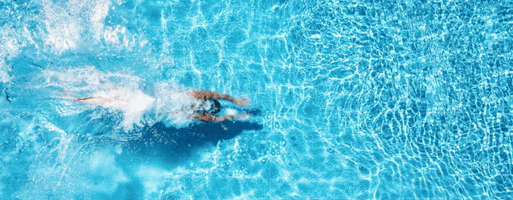 Overhead view of a person swimming in a jacuzzi swim spa, showcasing the water's surface and surrounding area.